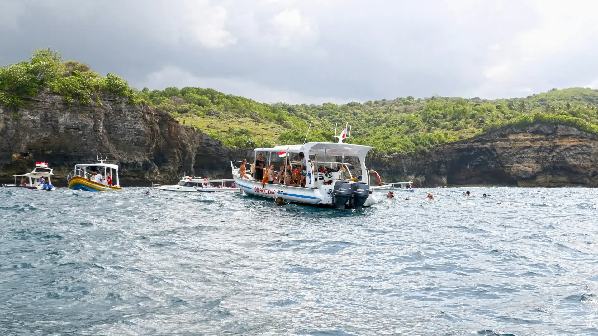 A group of people on a private boat tour near a beautiful, green shoreline in Nusa Penida, Bali