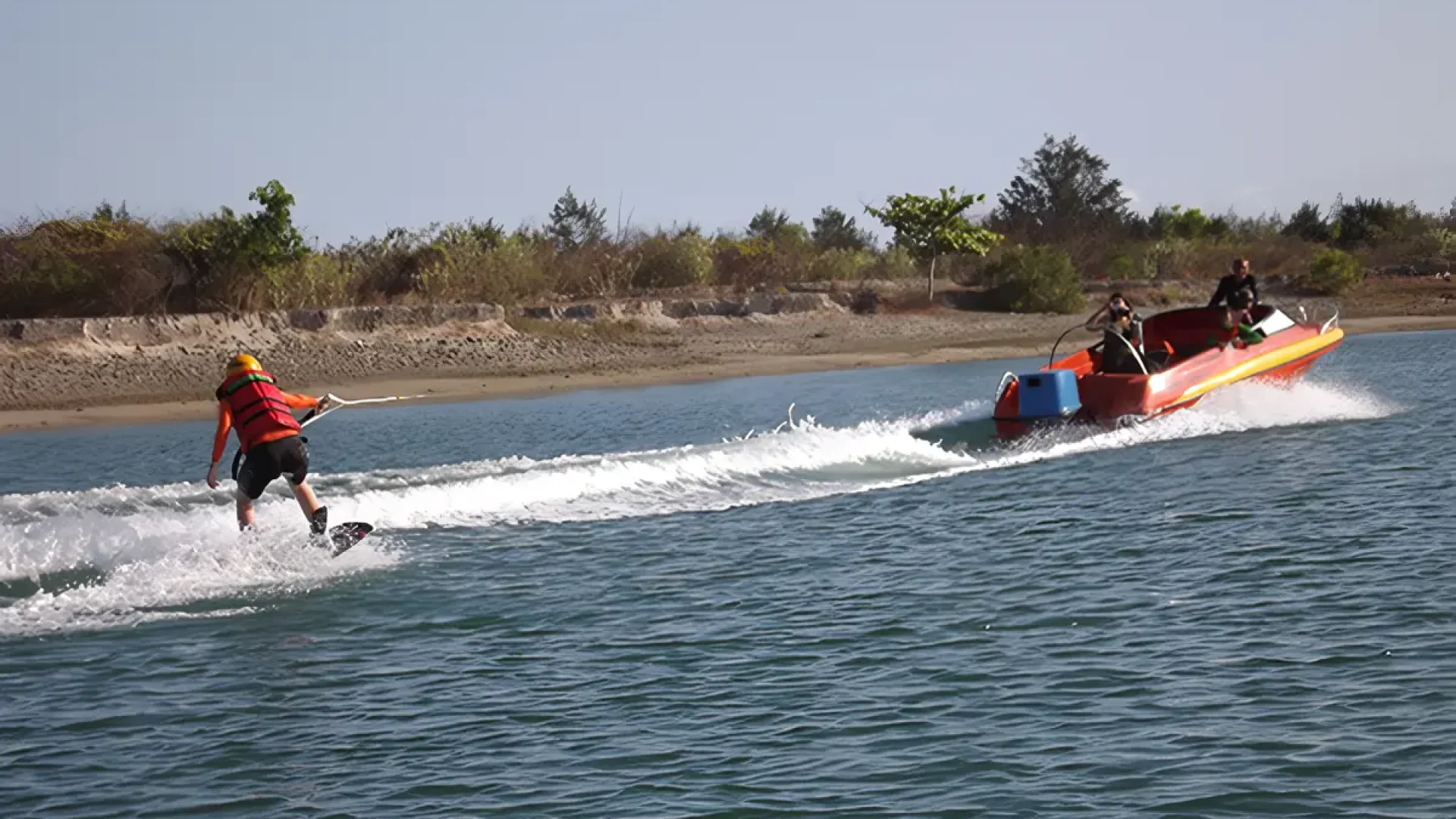 A person wakeboarding behind a speedboat in the waters of Sanur, Bali.